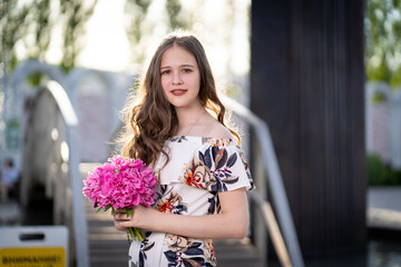cheerful girl in a light summer dress against the background of a city park