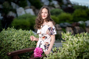 cheerful girl in a light summer dress against the background of a city park