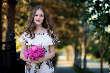 cheerful girl in a light summer dress against the background of a city park