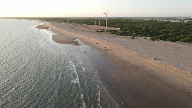 Aerial shot of golden beach meeting deep blue ocean water and foamy waves