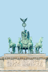 Quadriga, four horses lead by Viktoria, Roman goddess of victory at Brandenburg Gate (Brandenburger Tor) in Berlin historical downtown, Germany, at summer day, blue sky and copy space.