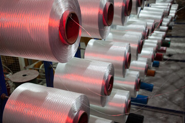 Rolls of polyester materrial on racks, ready to make rope in a factory.