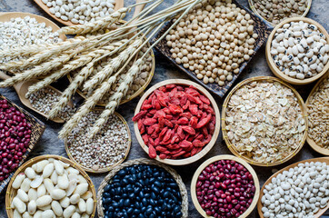 Top view of dry goji berry with soybean, millet, peanut, red and  black bean, lentils, rice, job's tear, and barley in wooden equipment on grunge background, for healthy food ingredient concept