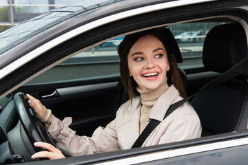 cheerful young woman looking away while driving automobile