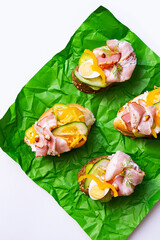 Smorrebrod with various stuffing. Trendy open sandwiches with cream cheese, quail eggs, tomatoes, bacon and vegetables. Modern, summer still life of healthy snacks.  Flat lay in minimalism style. 