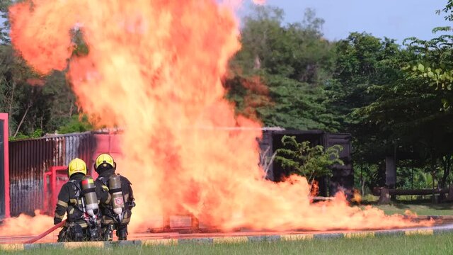 Side and back view one of fireman can not resist the heat of big fire on field and go out from practice of fire fighting during training.