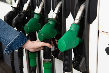 partial view of female hand near gasoline pistols on gas station