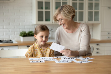 Curious small preschool kid girl learning math with middle aged caring grandmother. Happy older...