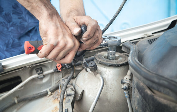 Mechanic repairing car with ratchet wrench.