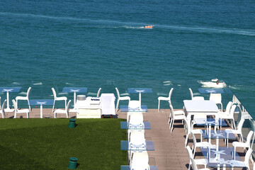 Obraz premium Panoramic terrace of an luxury Italian restaurant with a beautiful view over a blue sea. No people at tables. Modern white forniture. Adriatic sea, Italy.