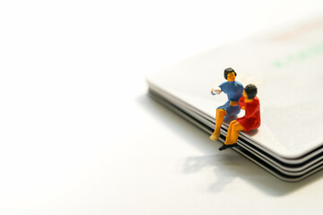 Miniature figure toy Business People sitting and discuss about business deal on stack of credit cards, Banking Finance Technology, Shopping and e-commerce concept