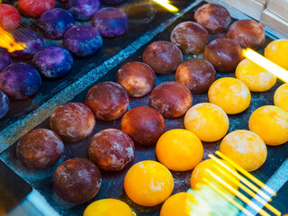 blue, brown and yellow Japanese ice cream mochi on display case with lamp glare
