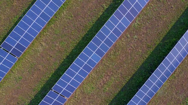 Blue photovoltaic batteries on an agricultural manicured field. Electricity to villages in the suburban area. The concept of reducing harmful waste. Zoom out. High quality. 4k footage.