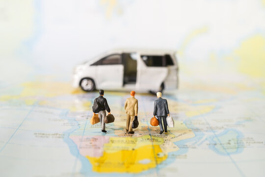 Miniature business people : businesses team walking to van car on world map with copy space for travel around the world, business trip traveler adviser agency or online world wide marketing concept.