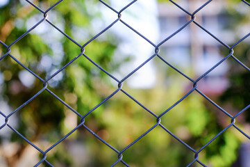 Fence made of wire mesh with bokeh blur background.