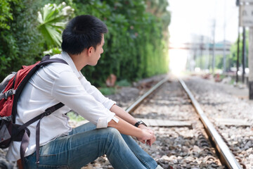 Obraz premium portrait of asian man, Young traveler with backpack in the railway, the train station with a traveler, Travel concept 