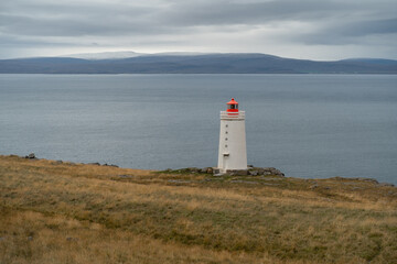 Fototapeta na wymiar Lighthouse on the cliff near the ocean in Northwest Iceland