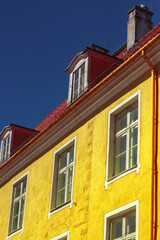 Facade of the old bright yellow arcitecture building with red foof in the center of Old Town. Tourism