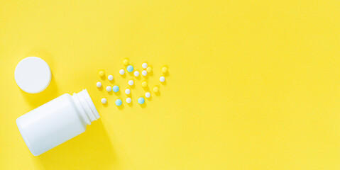 White pills and white bottle with copy space on yellow background, Healthy and Medicine concept.,colorful pills and drugs in close up.assorted pills and capsules in medicine. drugs of various kinds an