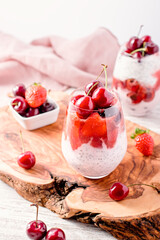 Chia seeds, cherry and strawberry layered pudding in glasses on table