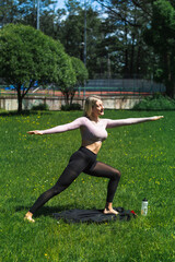 Young caucasian blond-haired woman in sportswear is doing yoga in the park. Outdoor workout. Yoga poses	