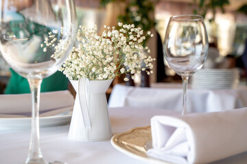 
a beautiful set table with dishes and glasses and a branch of gypsophila