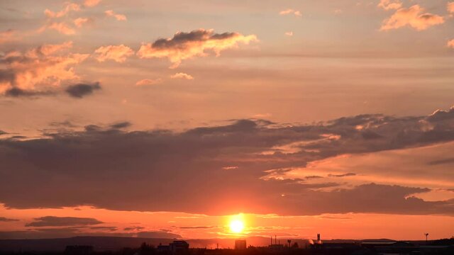 Sunset timelapse over the outskirts of a small town with moving clouds in the sky and teal orange tones. Zoom effect