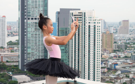 Ballet girl students are holding a smartphone in hand and taking a picture yourself photo on a high-rise building.