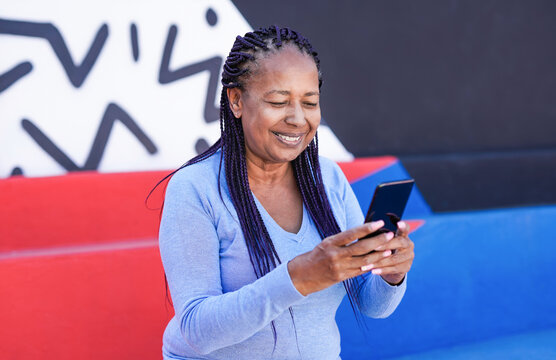 African american senior woman using mobile phone outdoor with colorful background