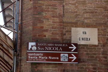 Tolentino, Italy. Directions sign to Basilica of San Nicola in San Nicola Street in Tolentino city. Sideways you see the building with the protections installed after the 2016 earthquake