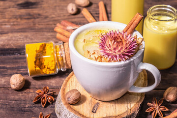 Golden turmeric milk with ice on bright yellow background