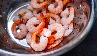 Close and selective focus on raw king prawns in a colander being cleaned and rinsed to make a home made prawn curry