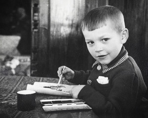 Retro portrait of Soviet boy drawing with paints on paper. Vintage black and white paper photo....