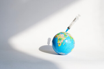 A small globe and a disposable syringe stuck into it. The concept of universal worldwide...