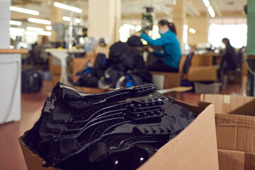 Closeup shot of lots of cut black lacquered leather details for future boots piled up in cardboard...