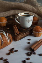 Fragrant coffee in a mug with cinnamon sticks and a fresh croissant, on a wooden background. View from above. Arabica, coffee, coffee beans, coffee break. 