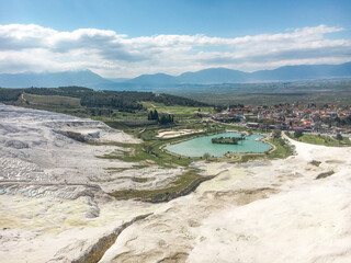 Fototapeta na wymiar Natural travertine pools aerial view to the village and mountains in Pamukkale, Turkey
