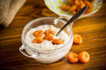 cooked boiled sweet oatmeal with dried apricots in a bowl