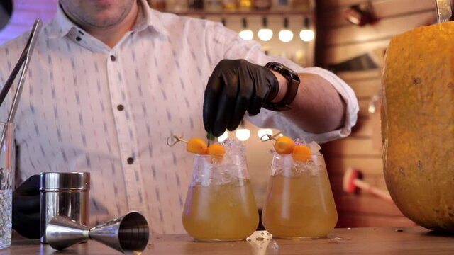 a man decorates a cocktail with a sprig of mint