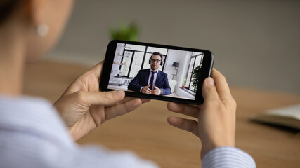 Shoulder back close up view young female worker holding video call talk or job interview conversation with skilled businessman boss leader hr manager, communicating remotely, enjoying virtual event.