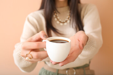 Young woman drinking coffee on color background, closeup