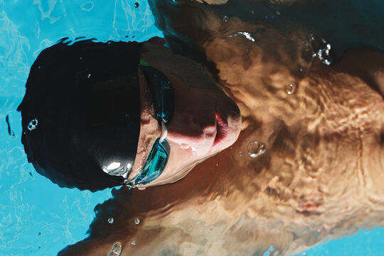 Sportsman in goggles swimming in pool during workout