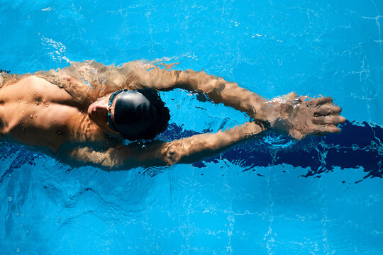 Sportsman in goggles swimming in pool during workout