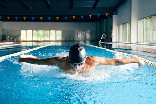 Sportsman in goggles swimming in pool during training