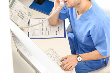 Male receptionist talking by telephone in clinic