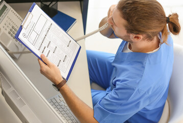 Male receptionist talking by telephone in clinic