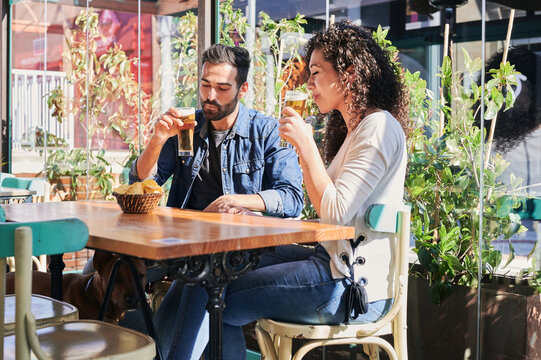 Happy ethnic couple with beer spending weekend in restaurant