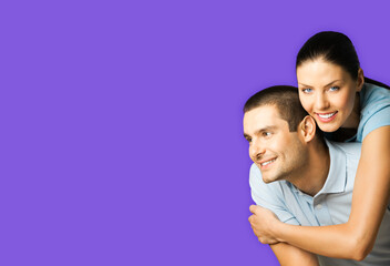 Portrait of standing close embracing couple in blue casual clothing, love studio concept, violet colour background. Young brunette man and woman posing together. Copy space area for slogan or text.