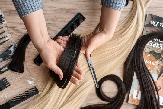 Female hairdresser with strand of brunette hair in beauty salon