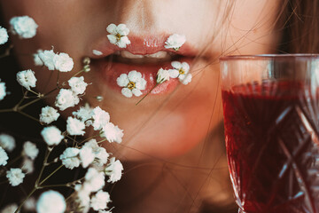female lips with little flowers and Graceful glass with red cherry or Strawberry liqueur. Gentle alcohol aesthetics - 441773980